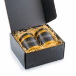 Offene schwarze Geschenkbox mit zwei Gläsern Golden Honey à 330 g und Holzwolle